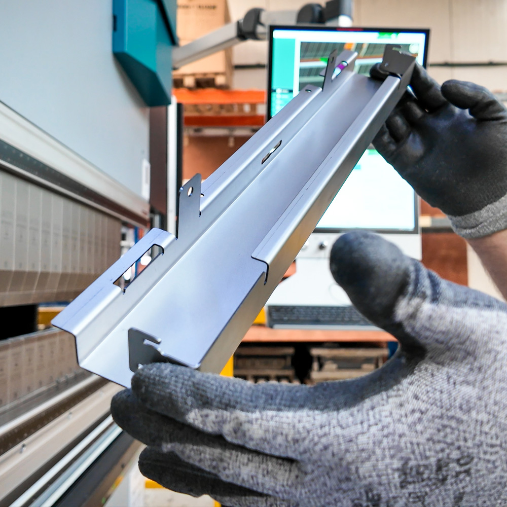 Schuine opname van een man die een metalen product vasthoudt tijdens de productie