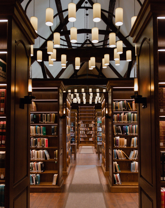 View of library wooden shelves with books, LED lighting and large chandeliers